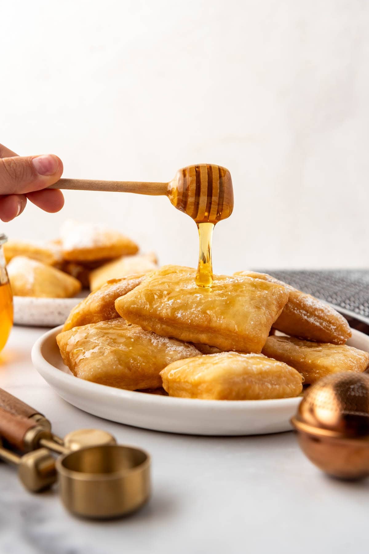 An image of honey being drizzled over a stack of warm sopapillas on a plate.