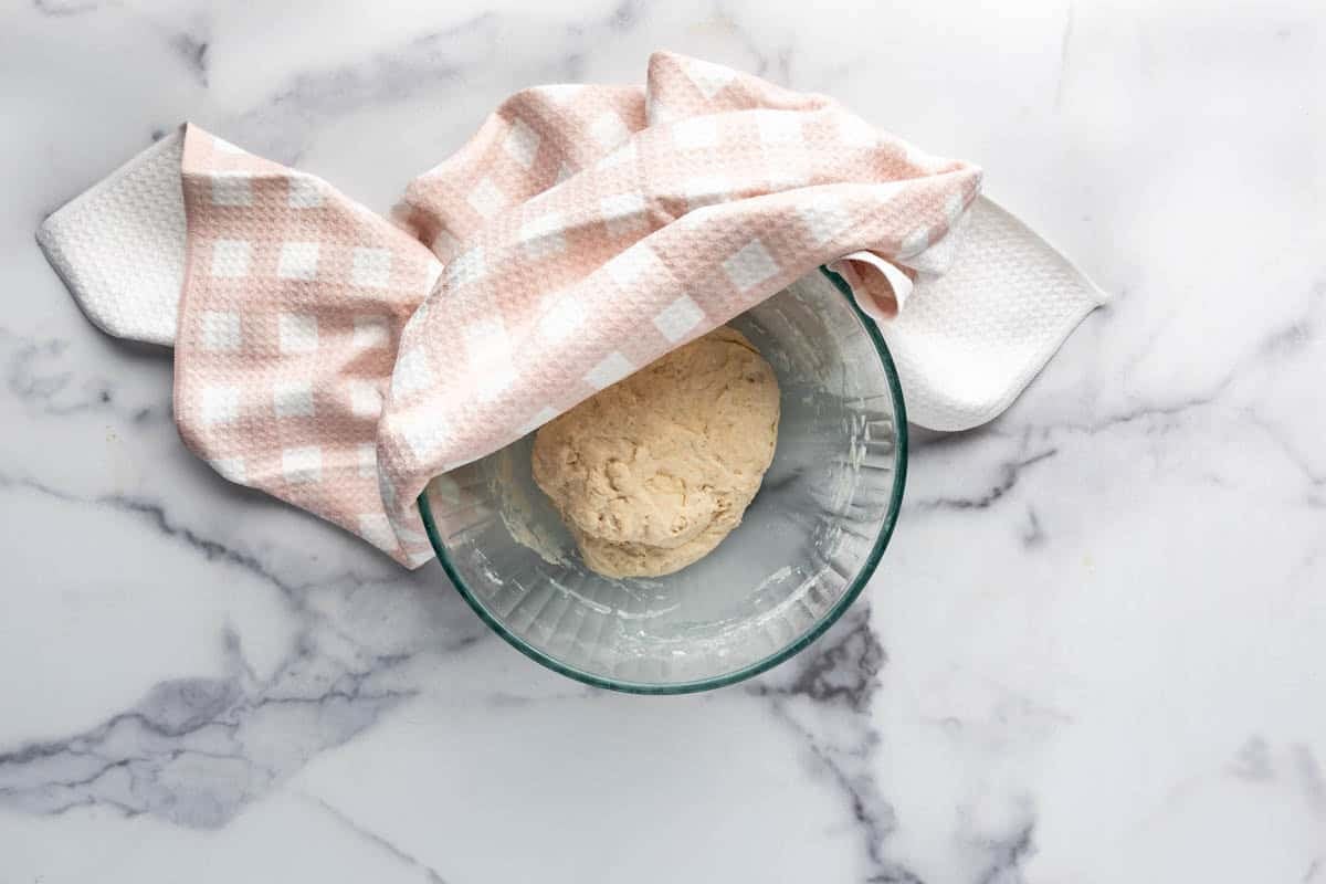 Sopapilla dough resting in a bowl covered with a dishcloth.