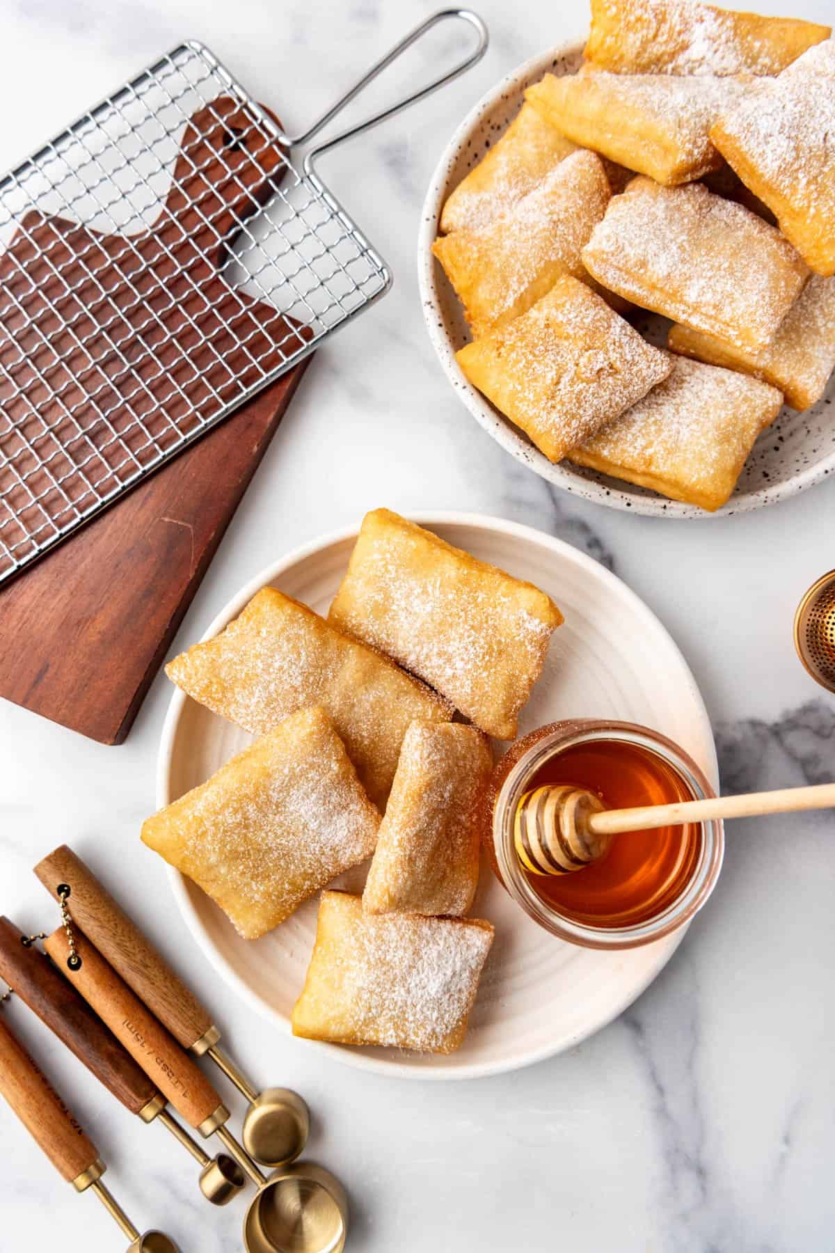 An overhead image of sopapillas on plates with honey nearby.