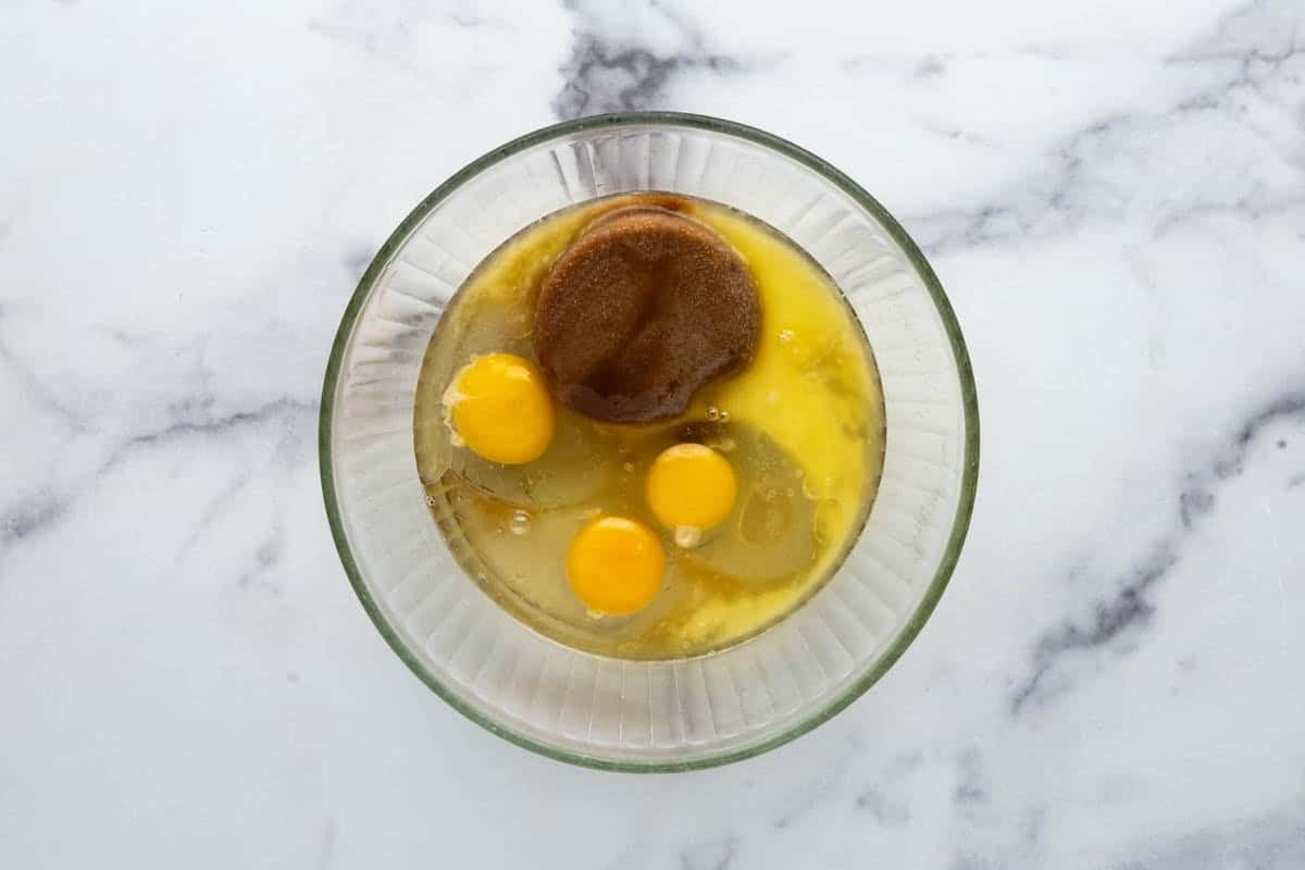 Combining eggs, cornstarch, melted butter, vanilla, and brown sugar in a glass mixing bowl.