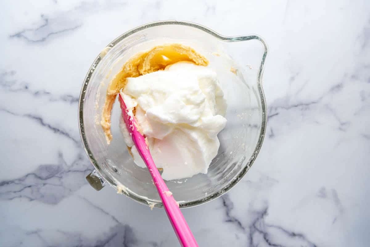 Folding whipped egg whites into cake batter.