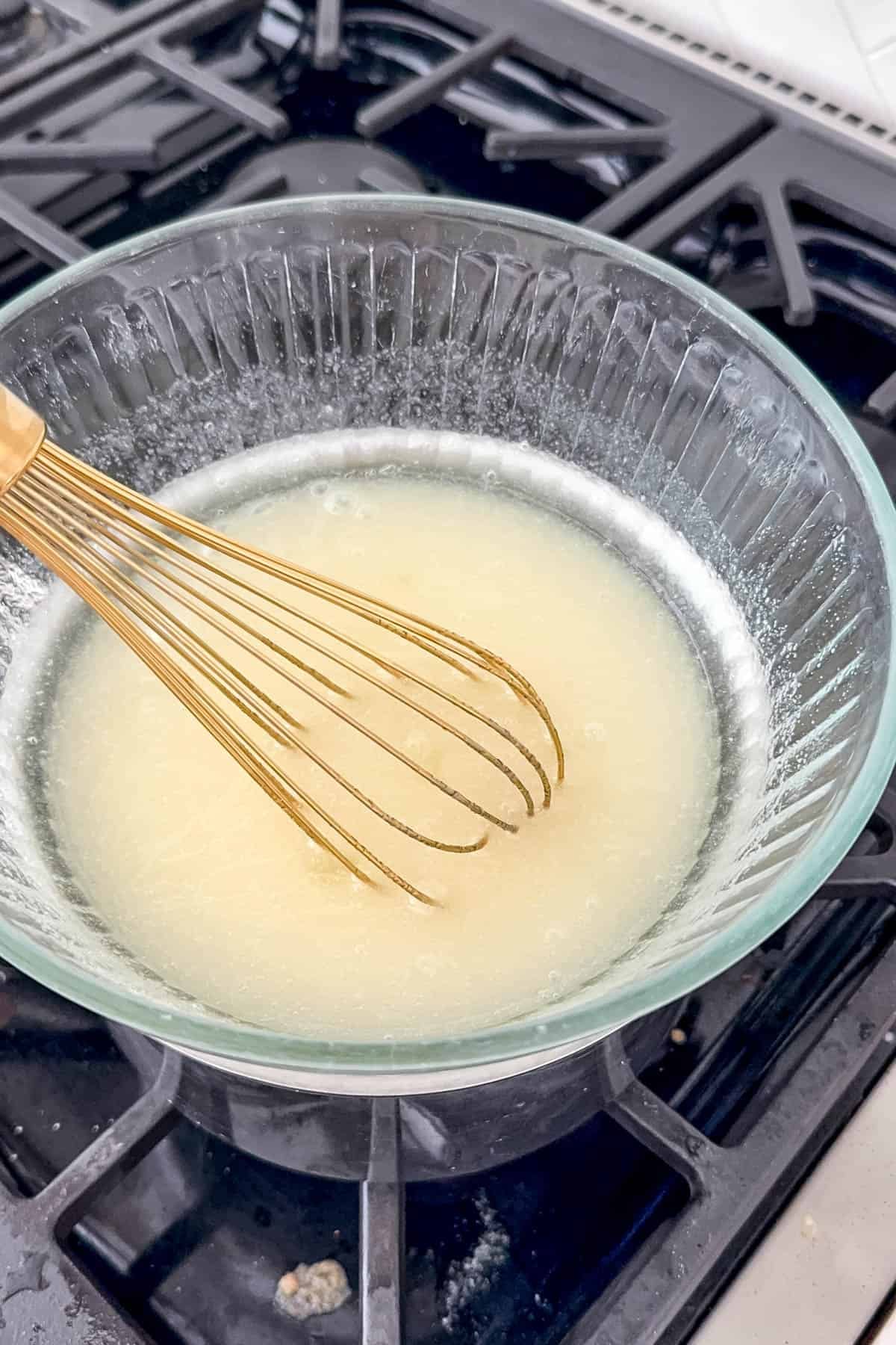 A whisk in a double boiler with ingredients for 7-minute frosting.