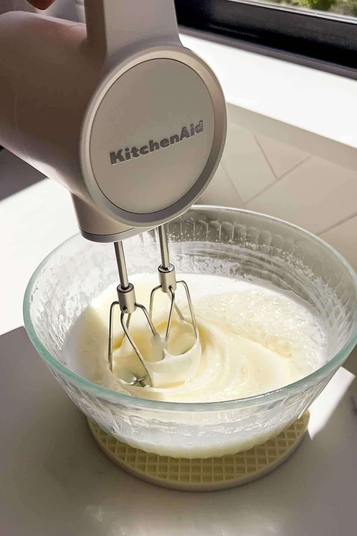 An electric mixer being used to beat 7-minute frosting.