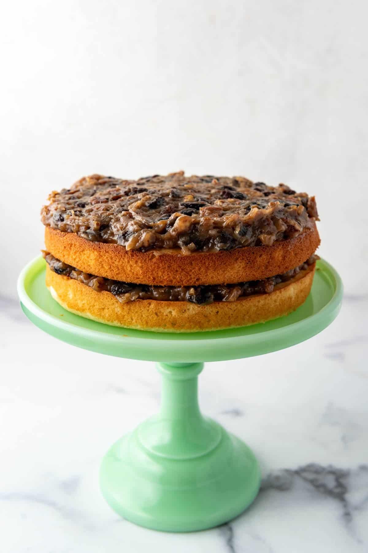 Two layers of cake with filling on a green cake stand.