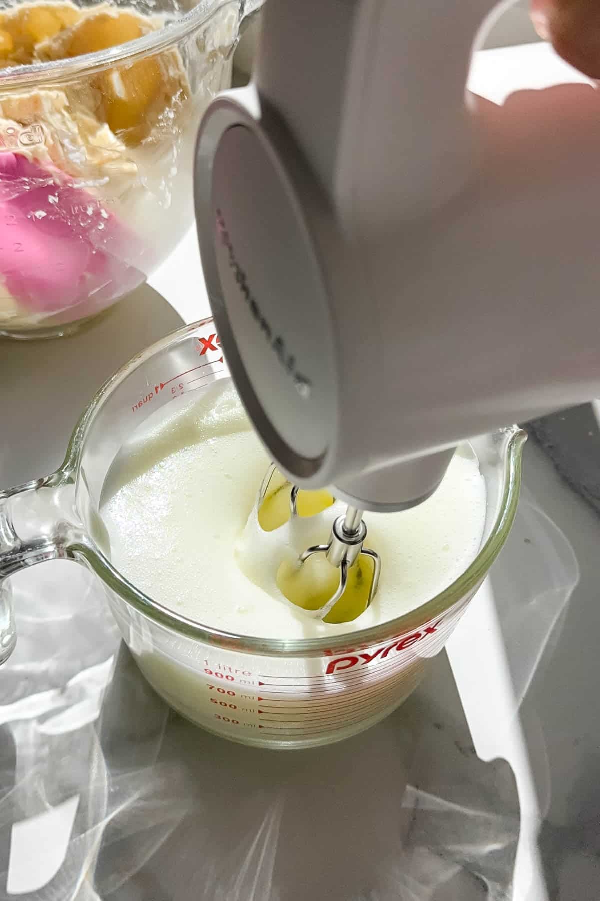A hand mixer being used to whip egg whites into stiff peaks.