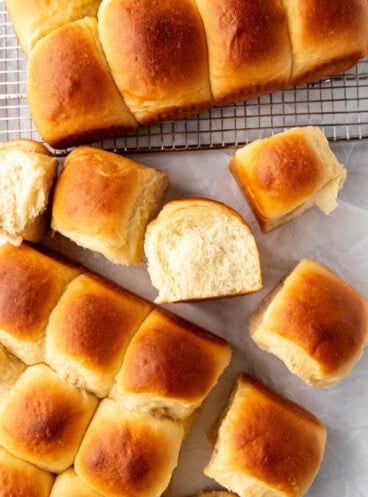 Homemade Hawaiian rolls with one of them turned on its side showing the soft fluffy interior.