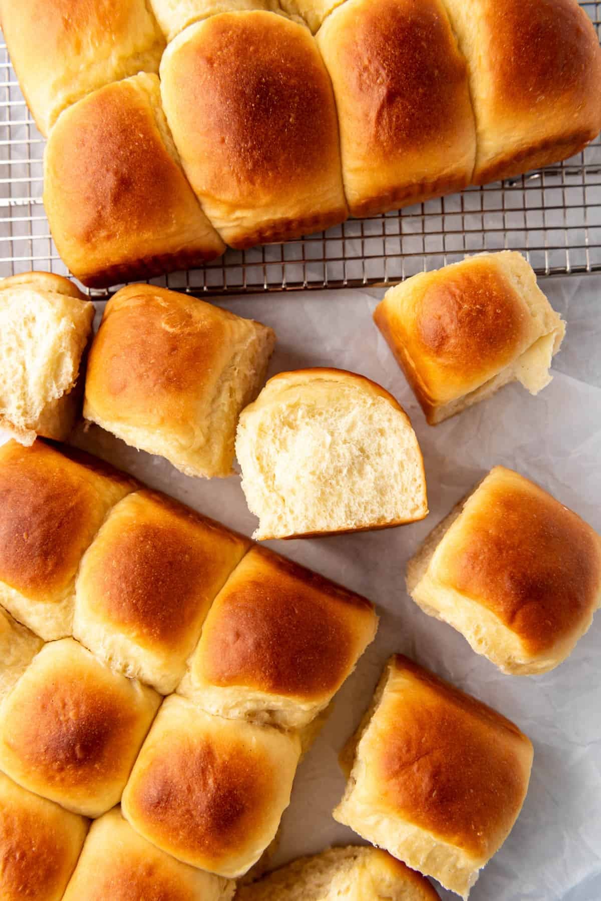 Homemade Hawaiian rolls with one of them turned on its side showing the soft fluffy interior.