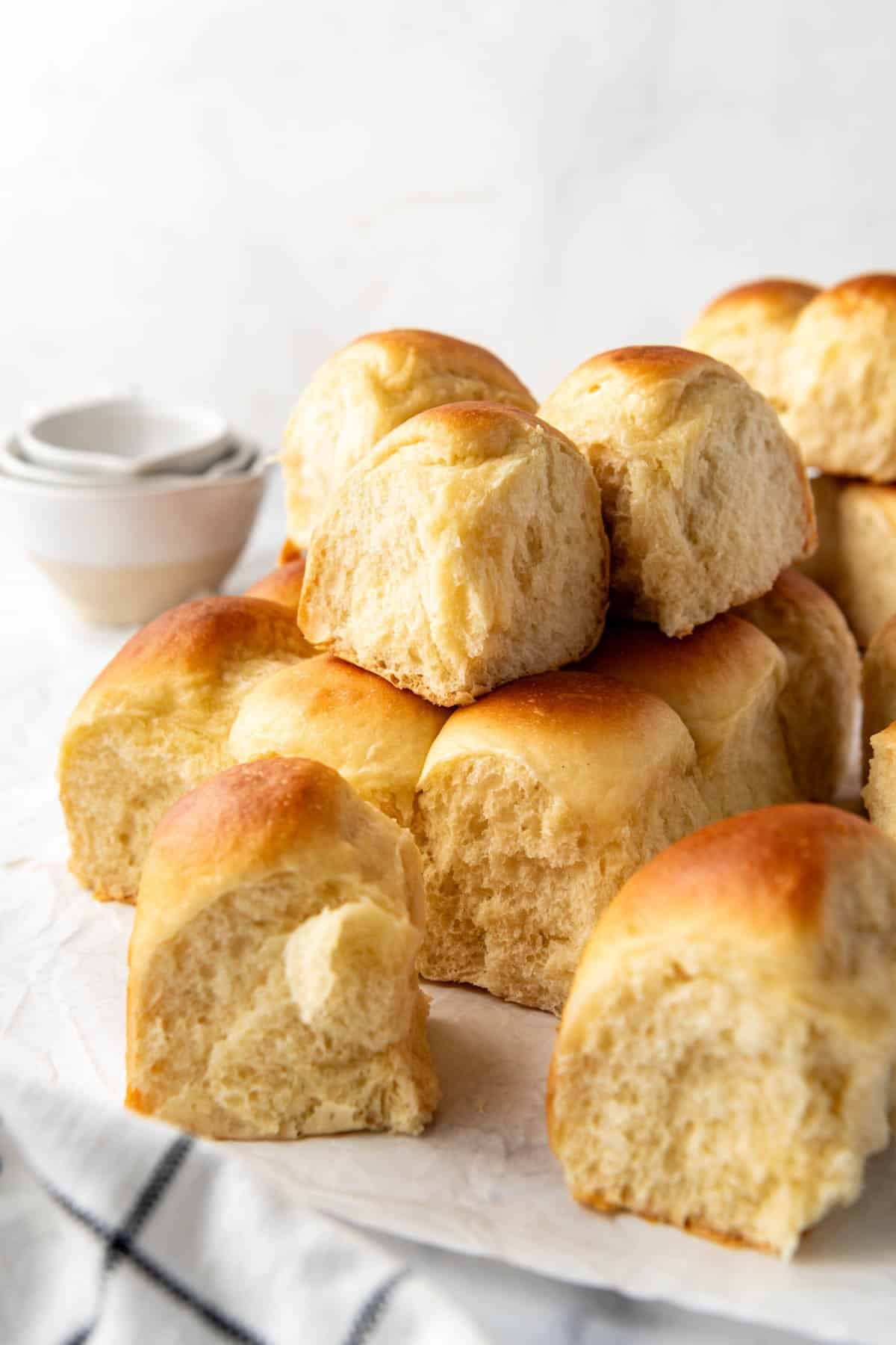 Stacked homemade Hawaiian rolls that have been torn apart and separated from each other.