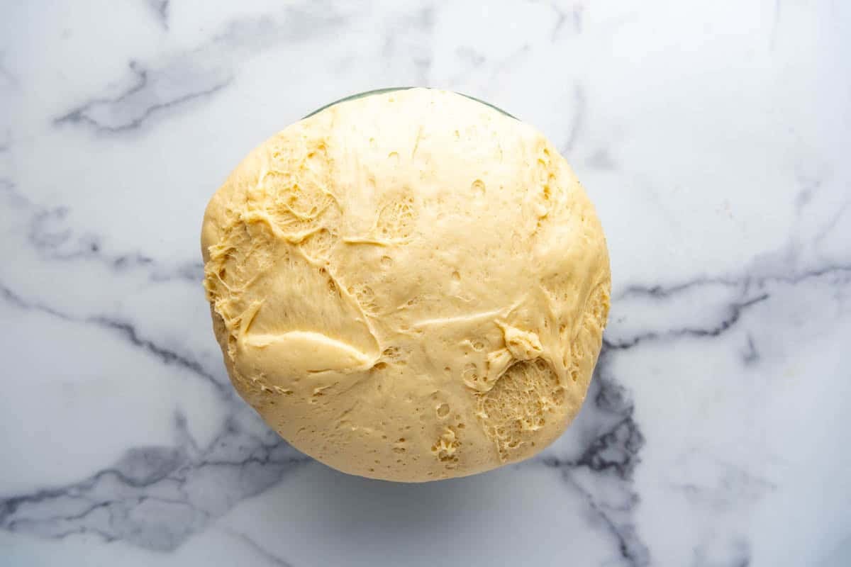 Homemade hawaiian roll dough that has risen in a bowl.