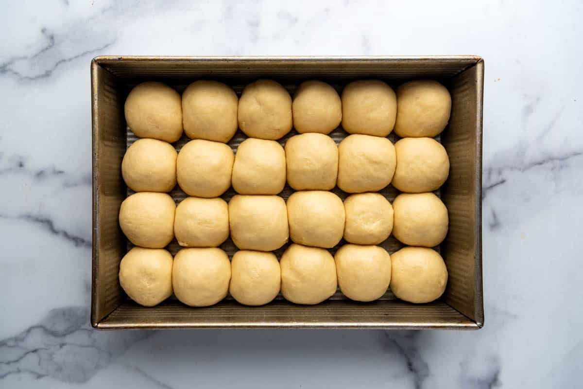 Puffy roll dough in a 9x13-inch pan ready to go into the oven.