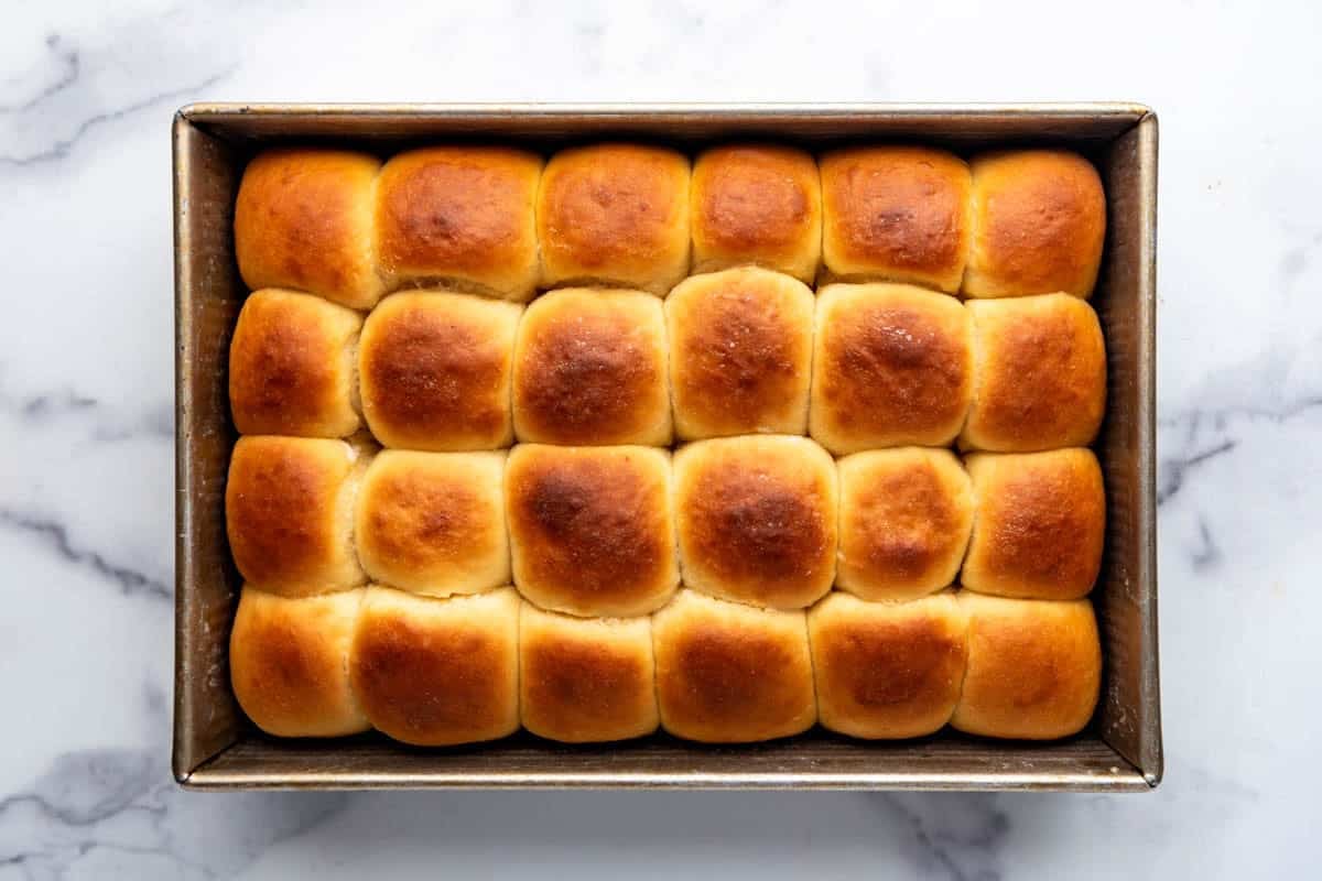 An overhead image of a pan of golden brown homemade Hawaiian rolls fresh out of the oven.