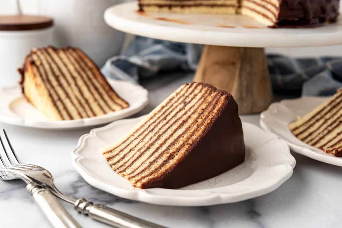 A slice of Smith Island cake on a white plate with more cake nearby.