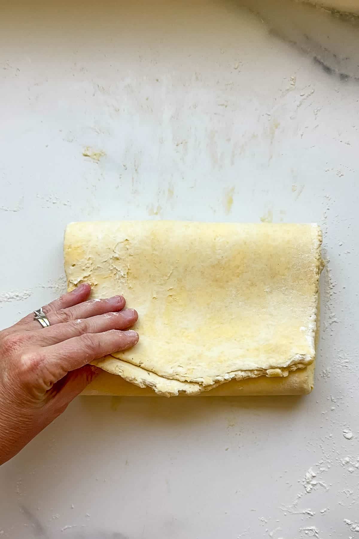 Folding kringle pastry dough into letter fold to laminate the dough.