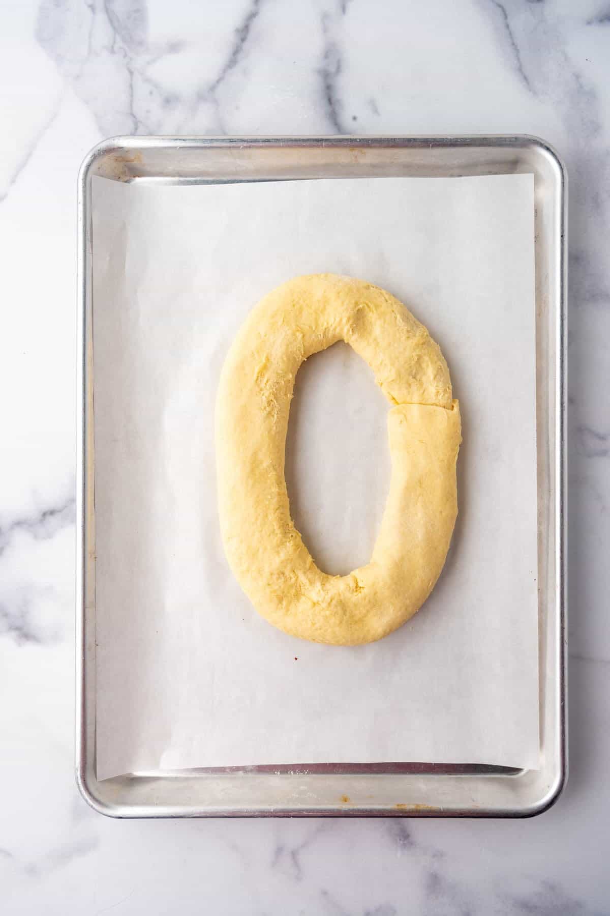 An oval-shaped kringle on a baking sheet ready to be baked.