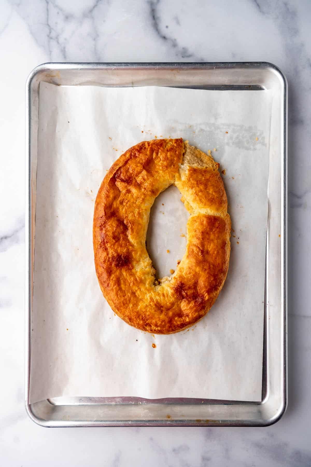 A baked kringle on a baking sheet lined with parchment paper before adding a simple glaze.