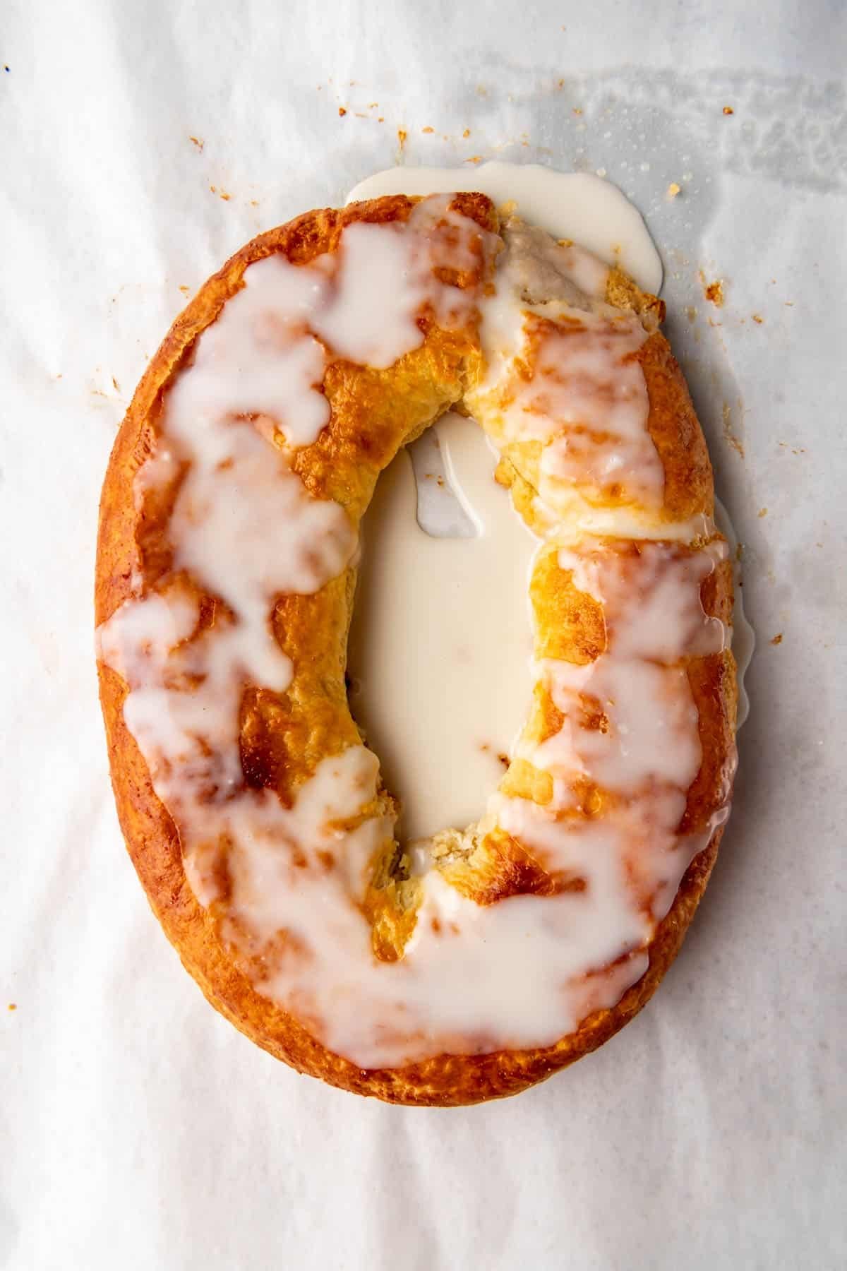 A close up image of a glazed almond kringle.