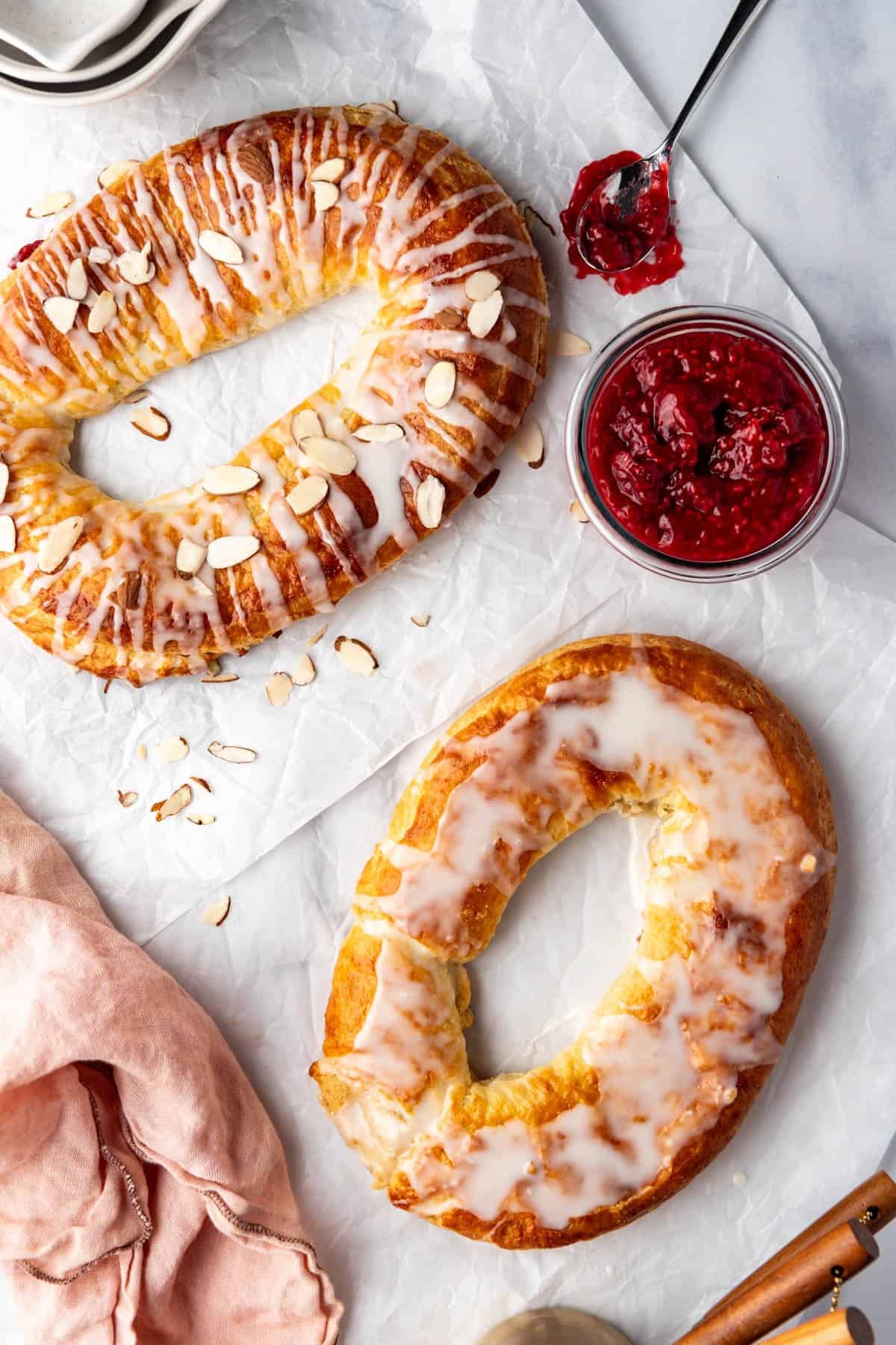 Two kringle flavors on a white surface with raspberry filling nearby.