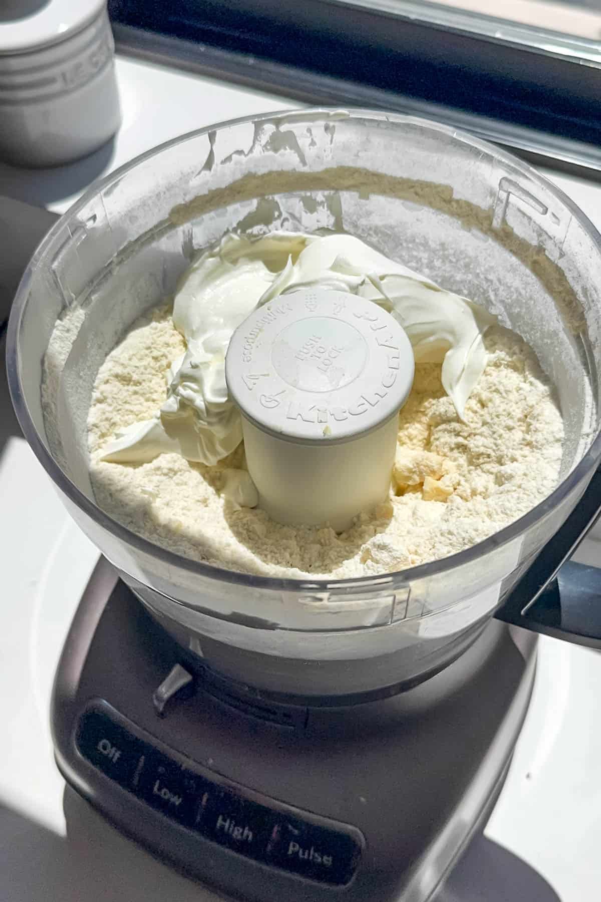 Adding sour cream to butter and flour in a food processor.