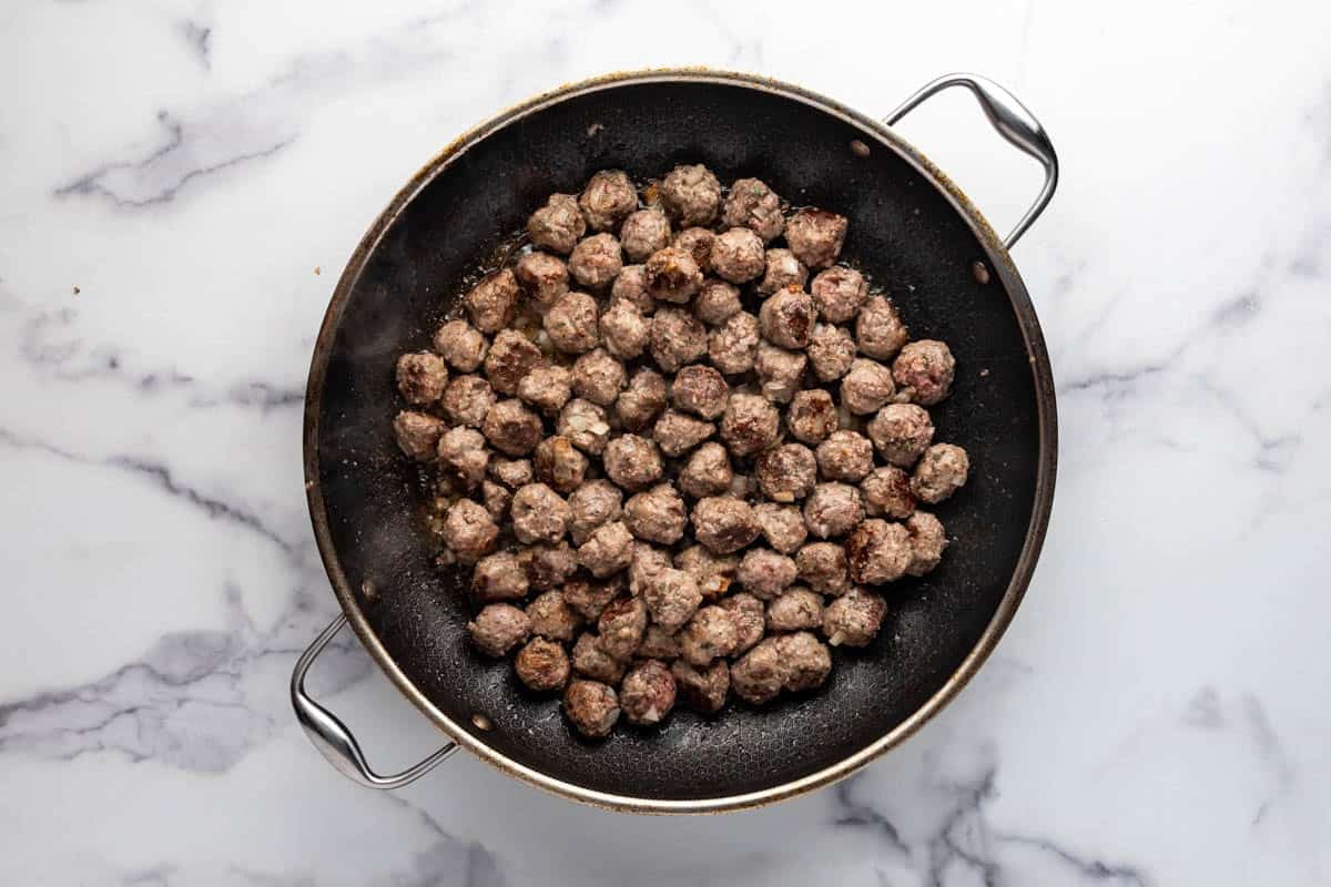 Browned mini meatballs in a large skillet.