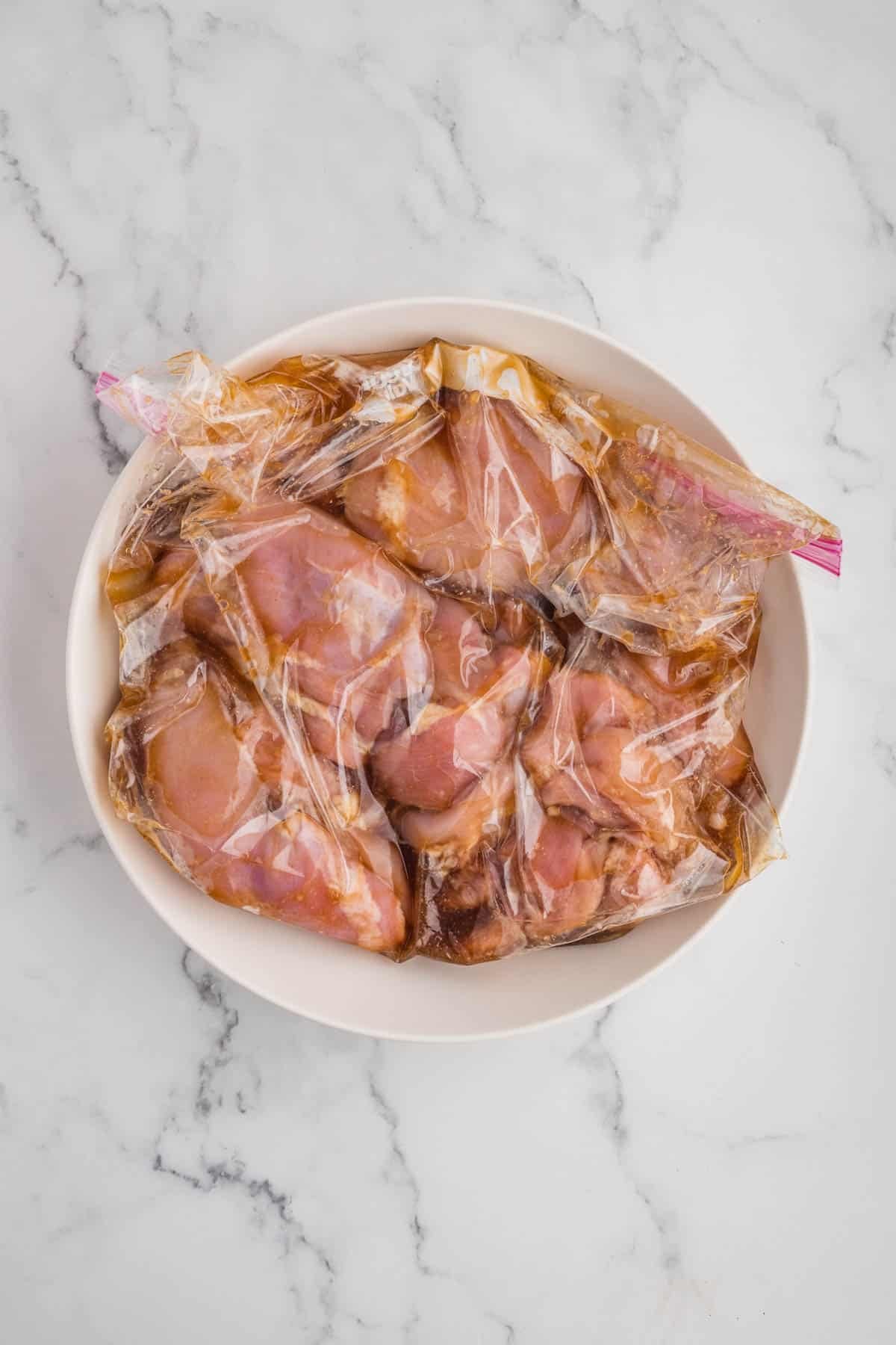 Chicken thighs marinating in a ziploc bag.