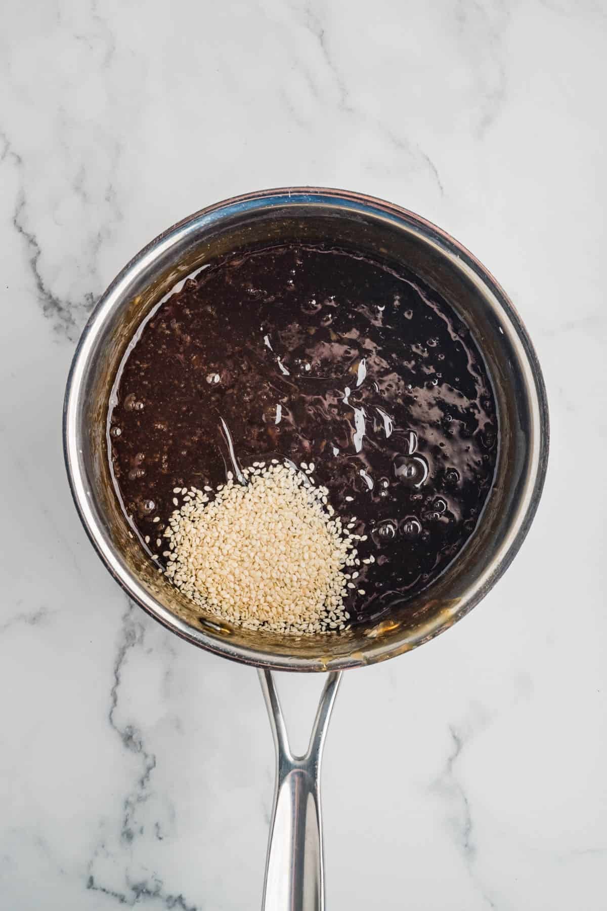 Adding sesame seeds to make homemade teriyaki sauce.