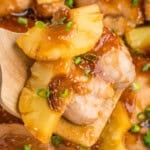 A wooden spoon holding baked teriyaki pineapple chicken.