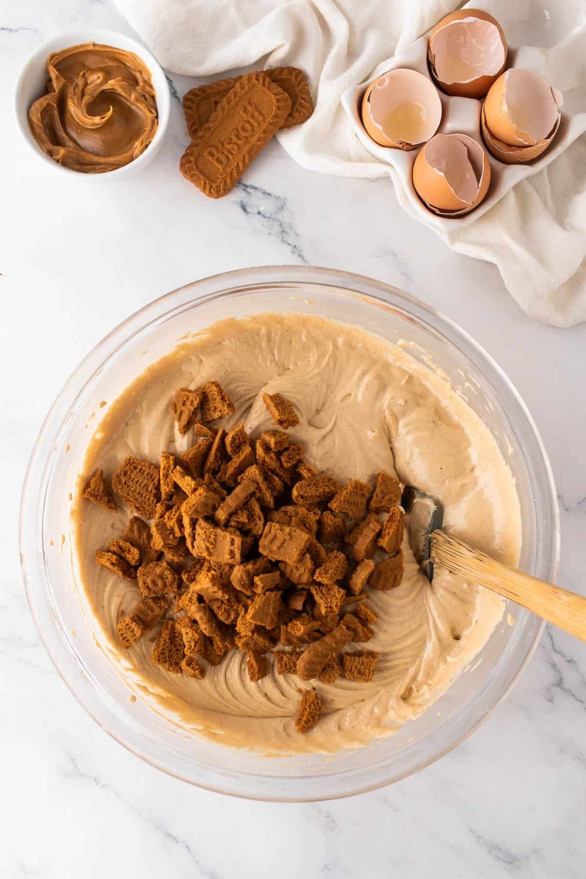 Adding chopped Biscoff cookies to cake batter in a mixing bowl.