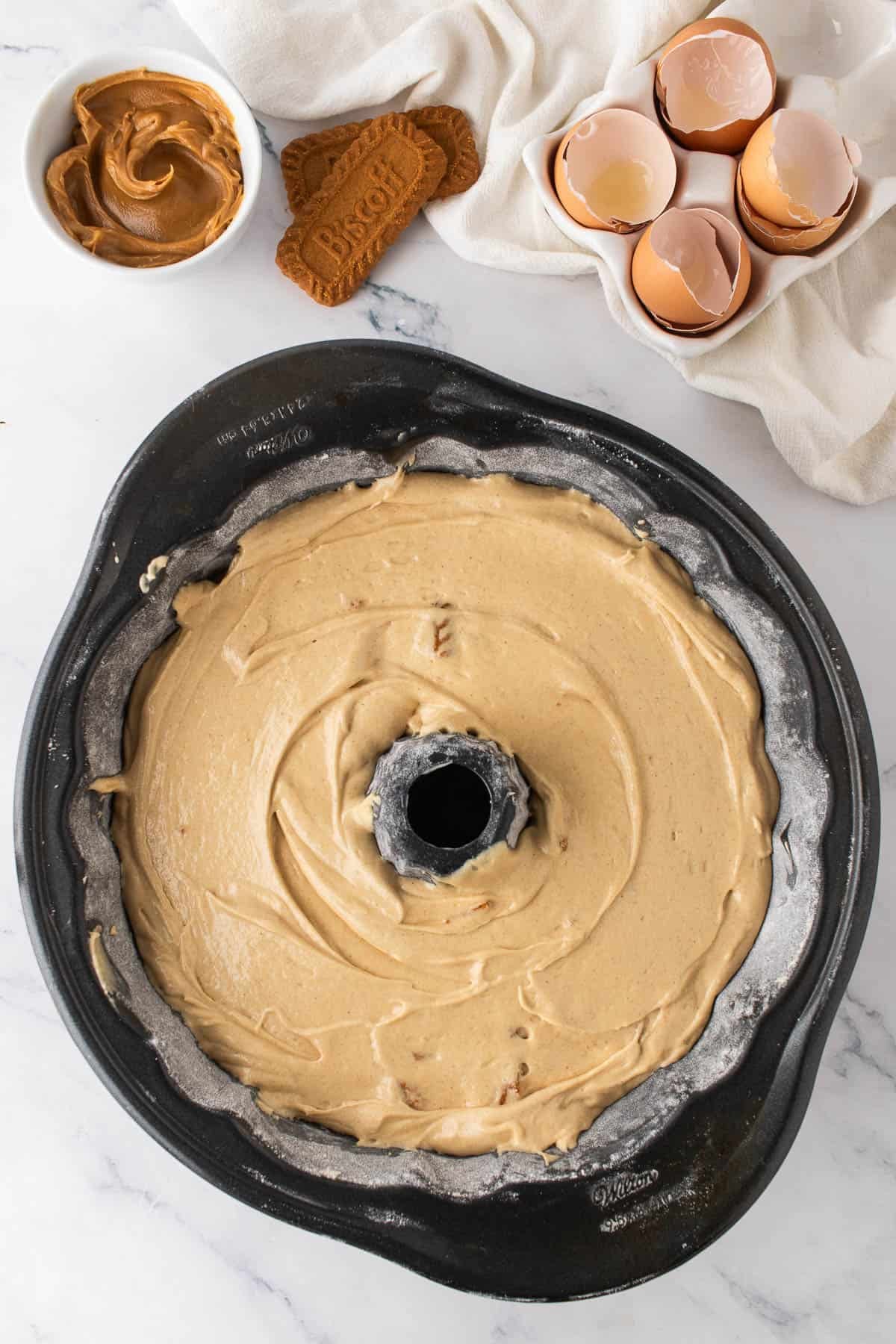 Adding cake batter to a bundt cake.