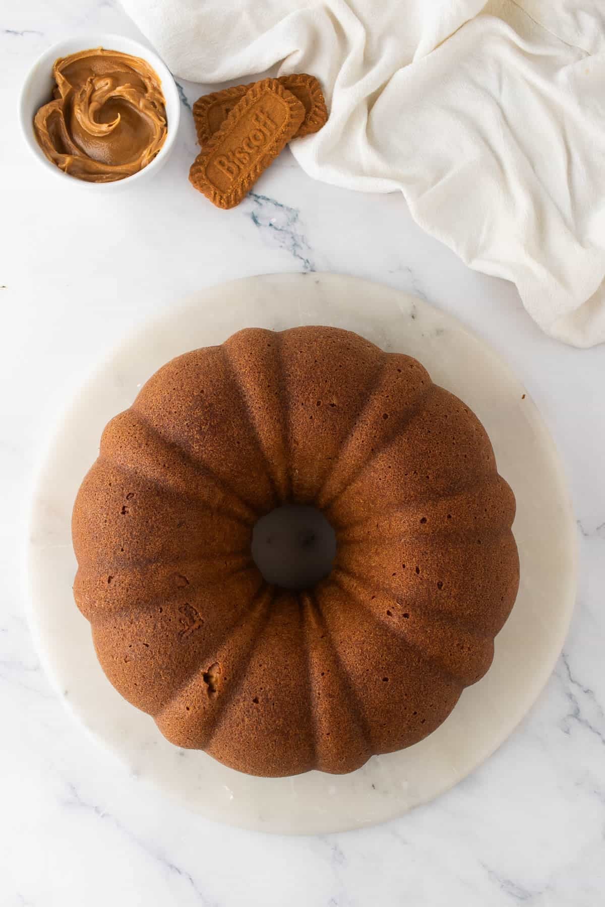 An overhead image of an undecorated biscoff cookie butter bundt cake on a cake stand.