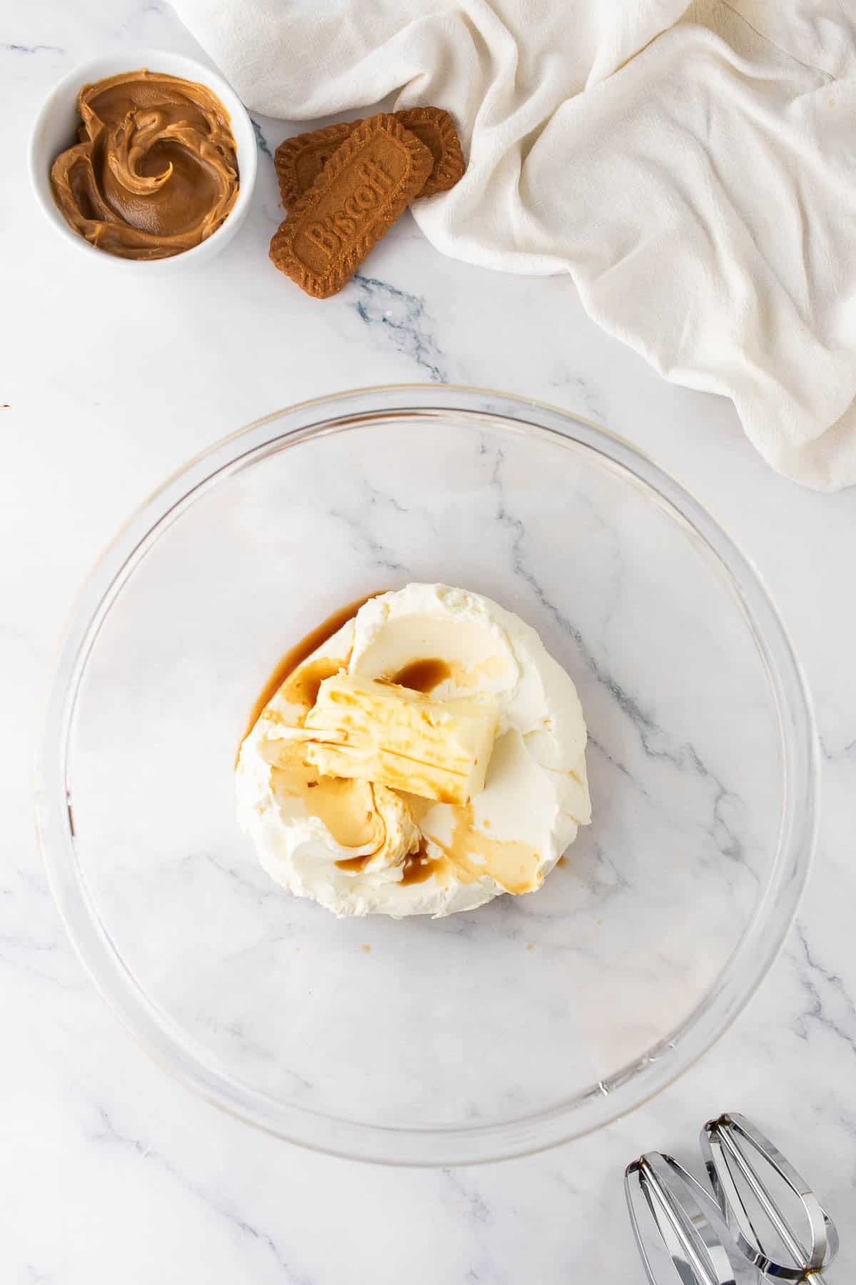 Combining butter, cream cheese, and vanilla in a bowl to make frosting.