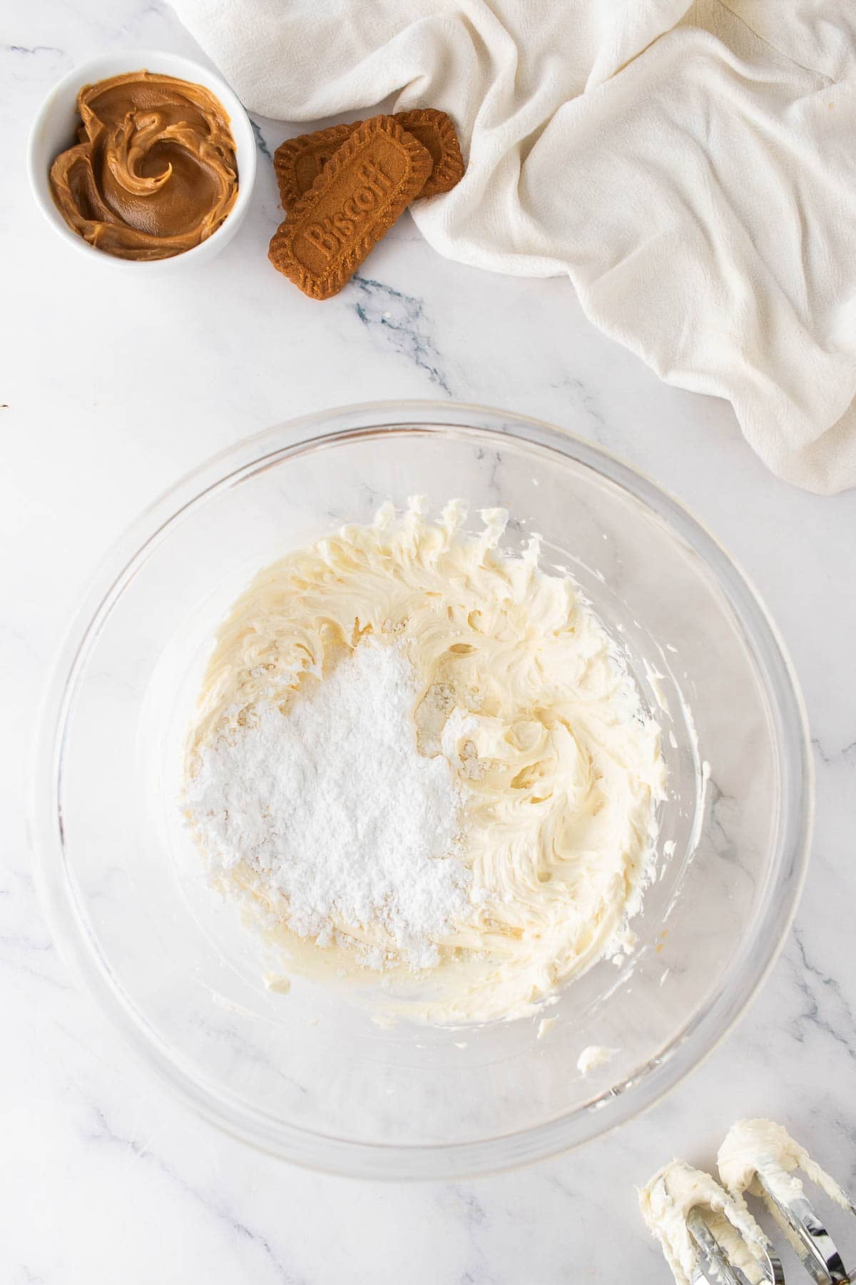 Adding powdered sugar to smooth cream cheese and butter for making frosting.