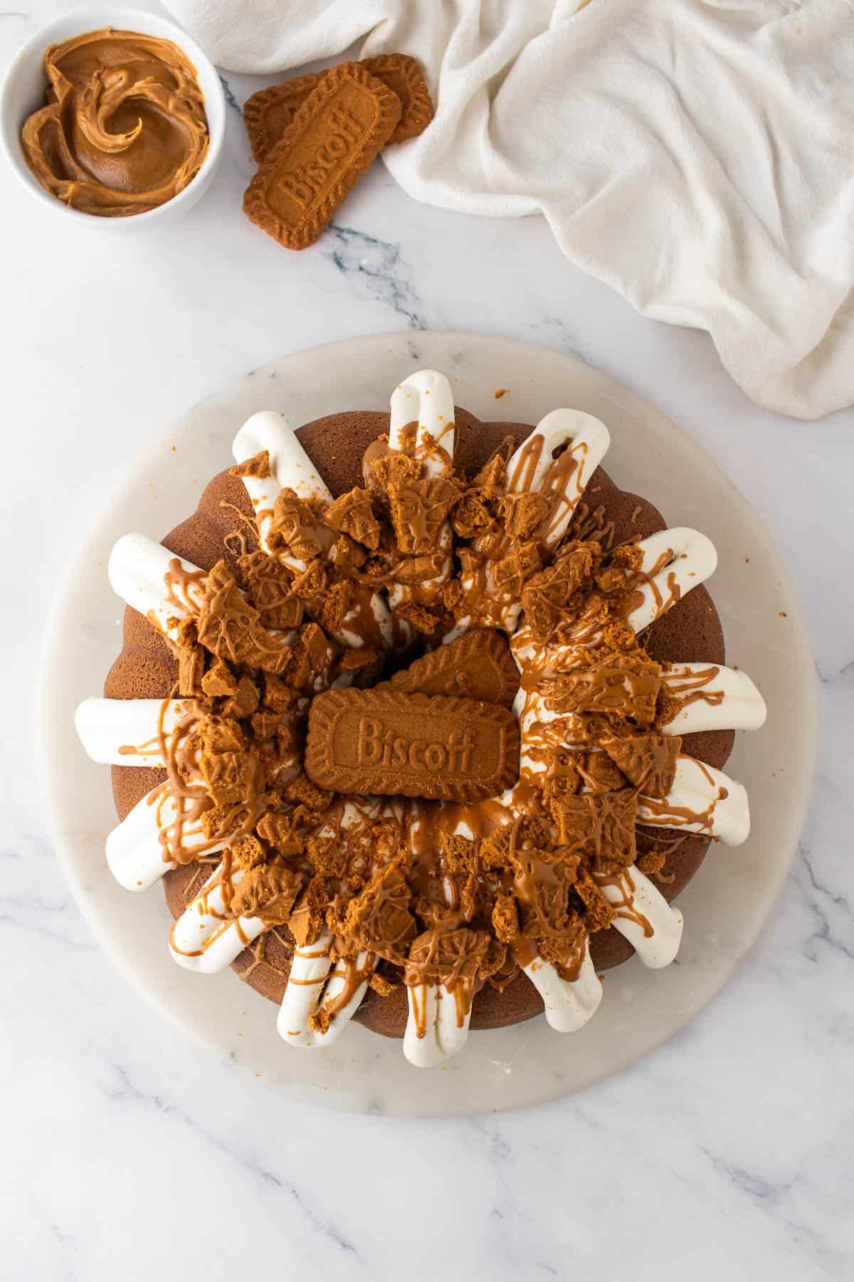 A decorated bundt cake topped with crushed Biscoff cookies and frosting.