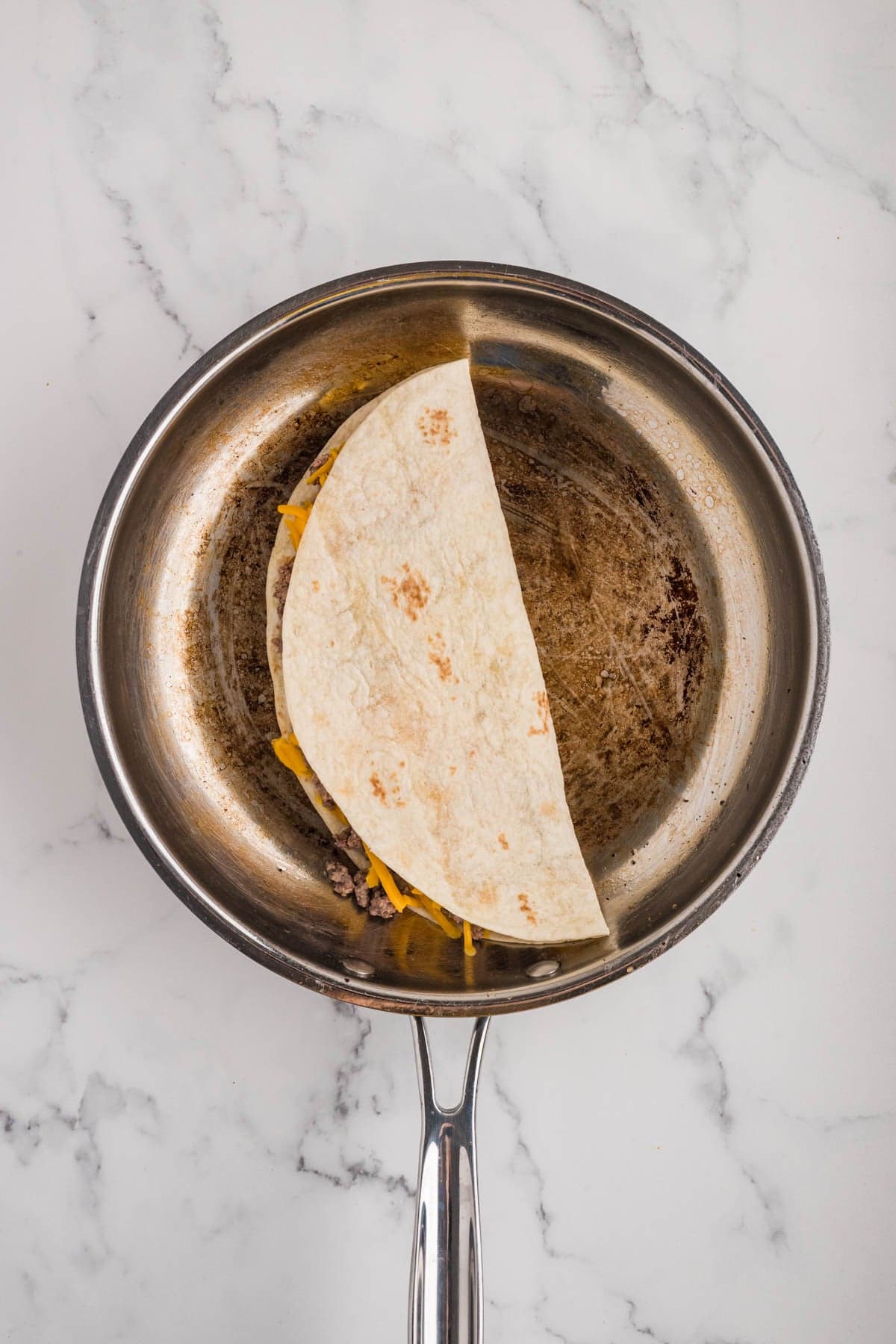 Grilled a cheeseburger quesadilla in a skillet.