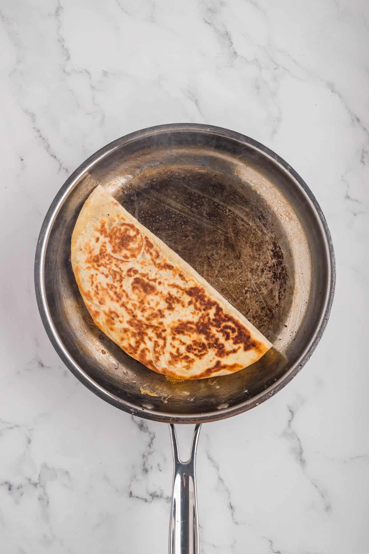 An overhead image of a quesadilla in a pan.