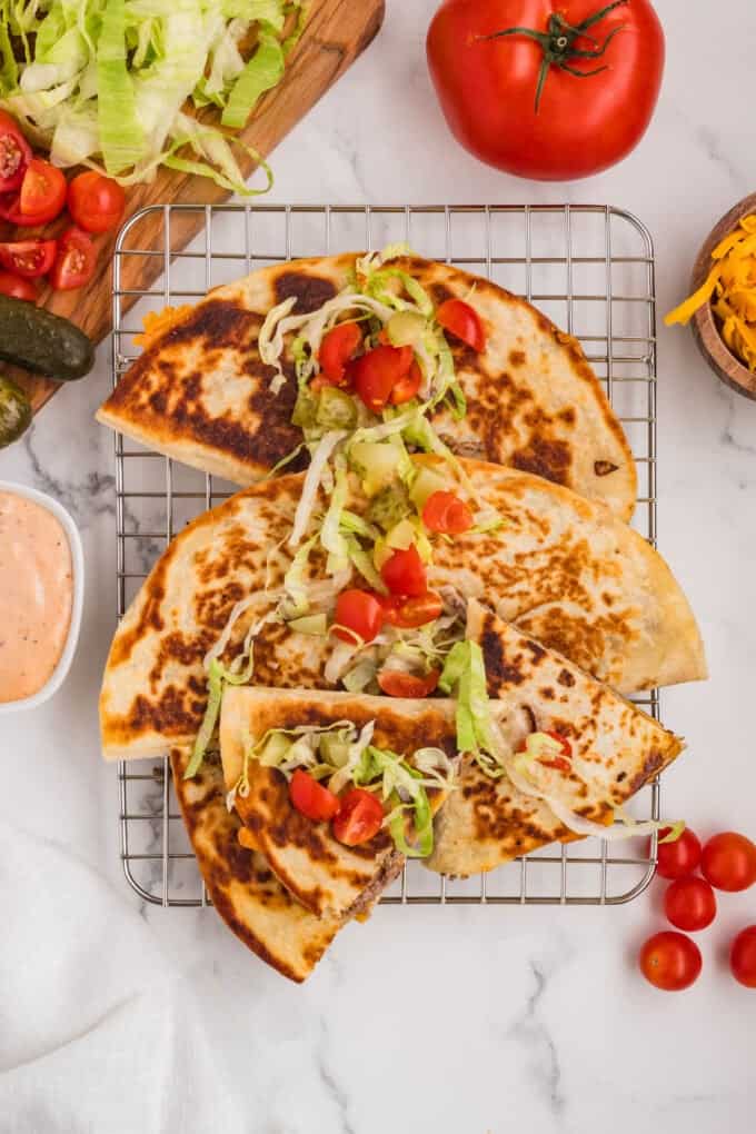 An overhead image of cheeseburger quesadillas with burger toppings on them.