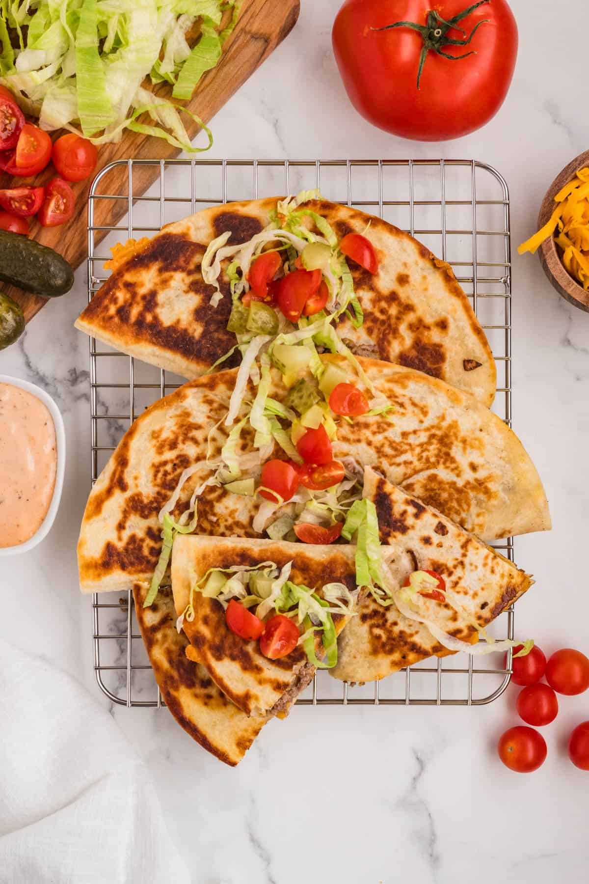 An overhead image of cheeseburger quesadillas with burger toppings on them.