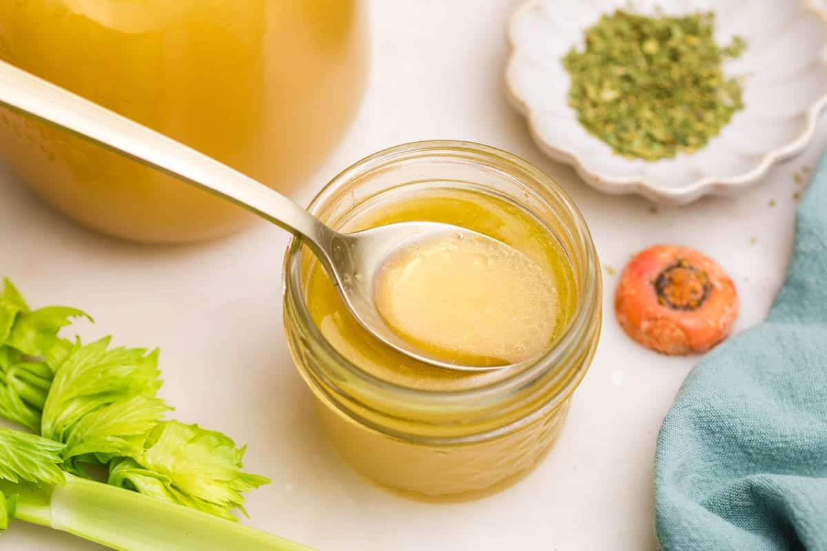An overhead image of a spoon in a jar of homemade chicken broth.