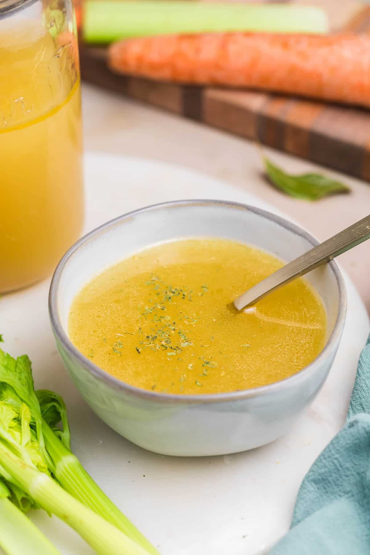 A bowl of homemade chicken broth with a spoon in it.