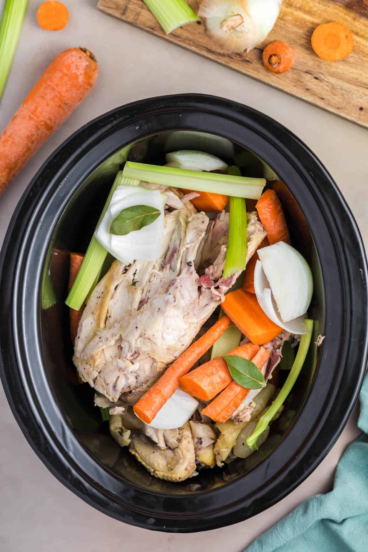 An overhead image of ingredients for homemade chicken broth in a slow cooker.