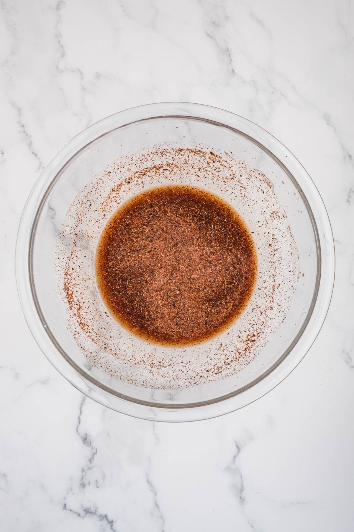Spices combined in a glass mixing bowl.