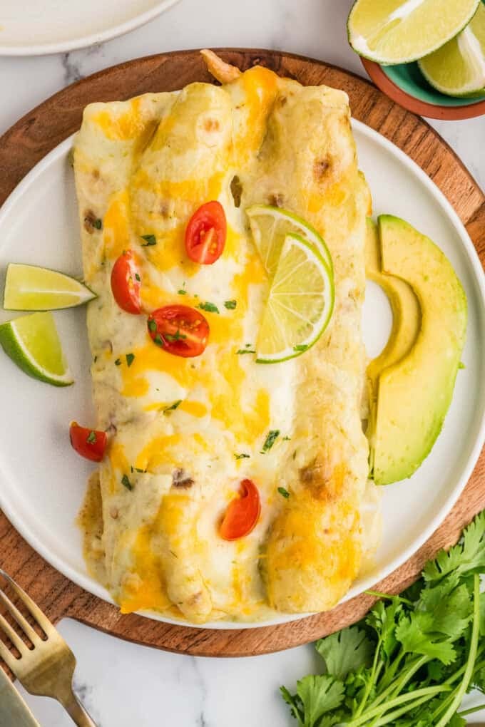An overhead image of two honey lime chicken enchiladas on a plate surrounded by toppings.