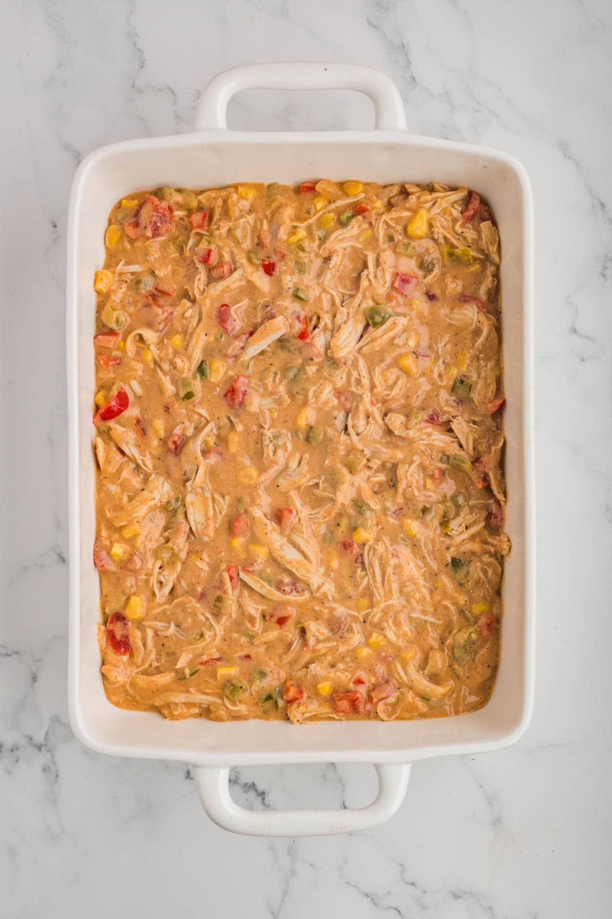 Half of the king ranch chicken filling to a casserole dish.