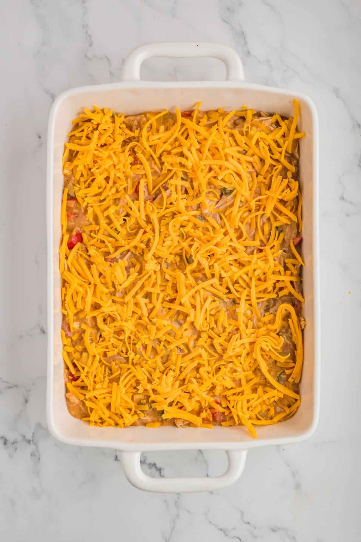 Adding shredded cheese to a casserole dish.
