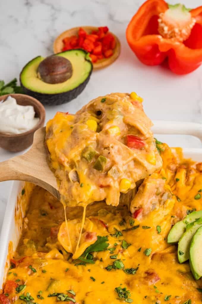 A serving spoon lifting a large scoop of king ranch chicken.
