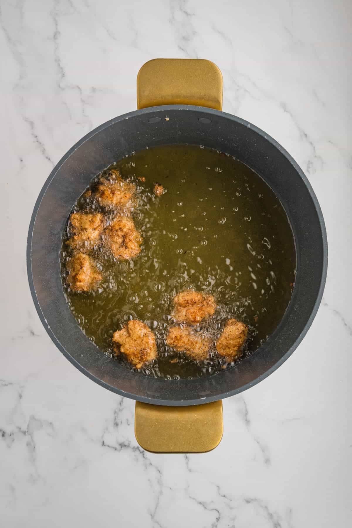 Frying popcorn chicken in a pot of boiling oil.