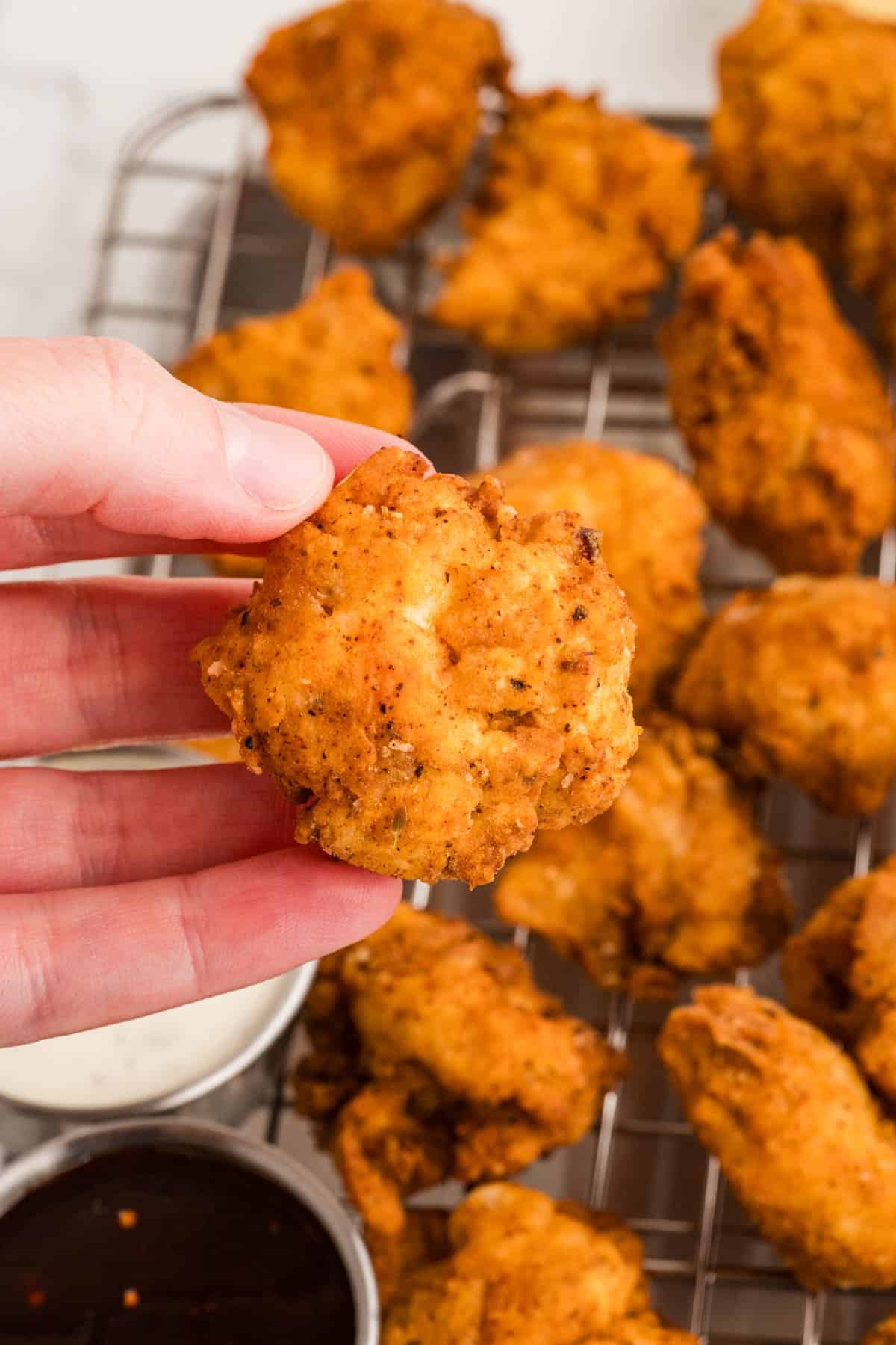A hand holding a piece of popcorn chicken.