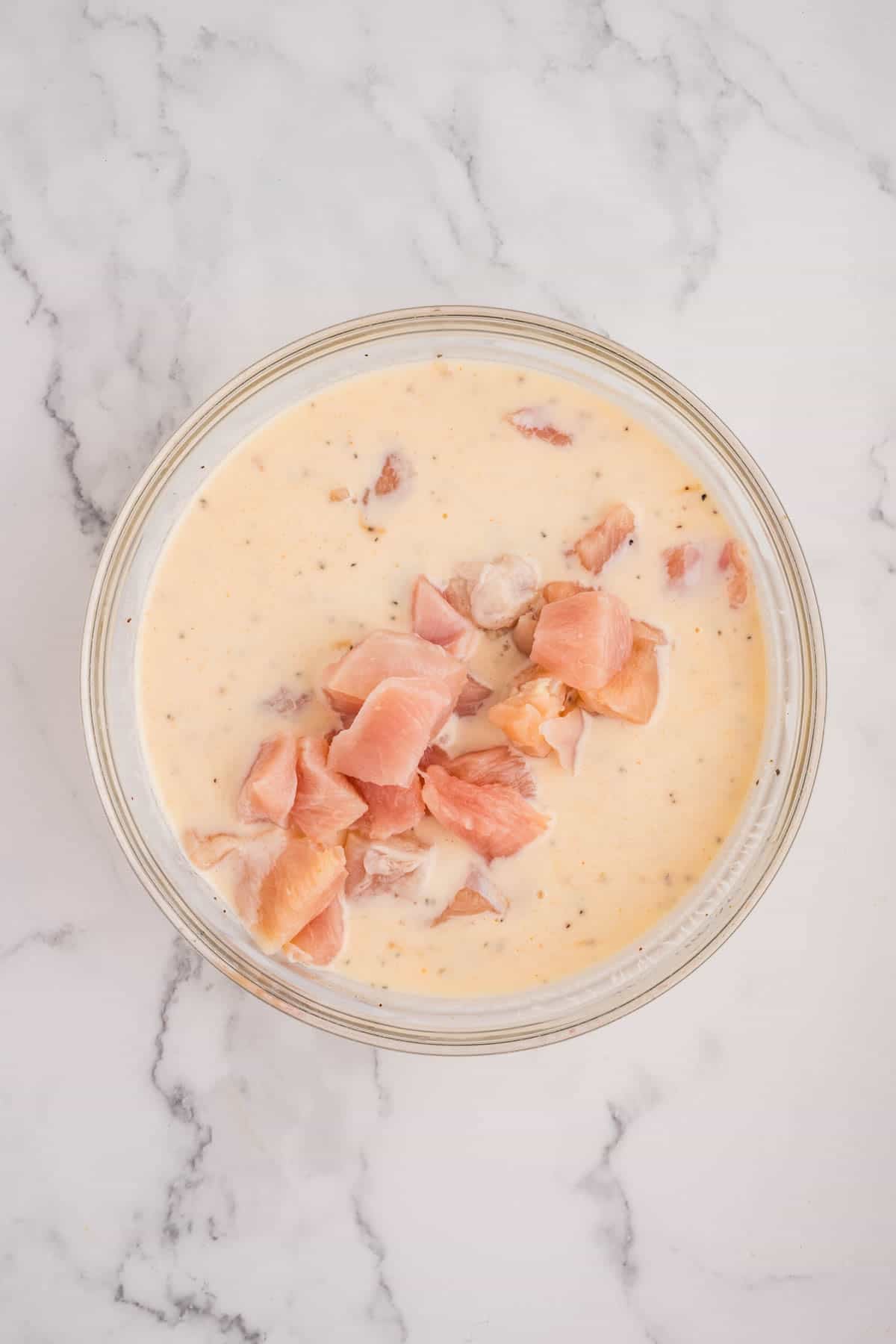 Bite size pieces of chicken marinating in a bowl.