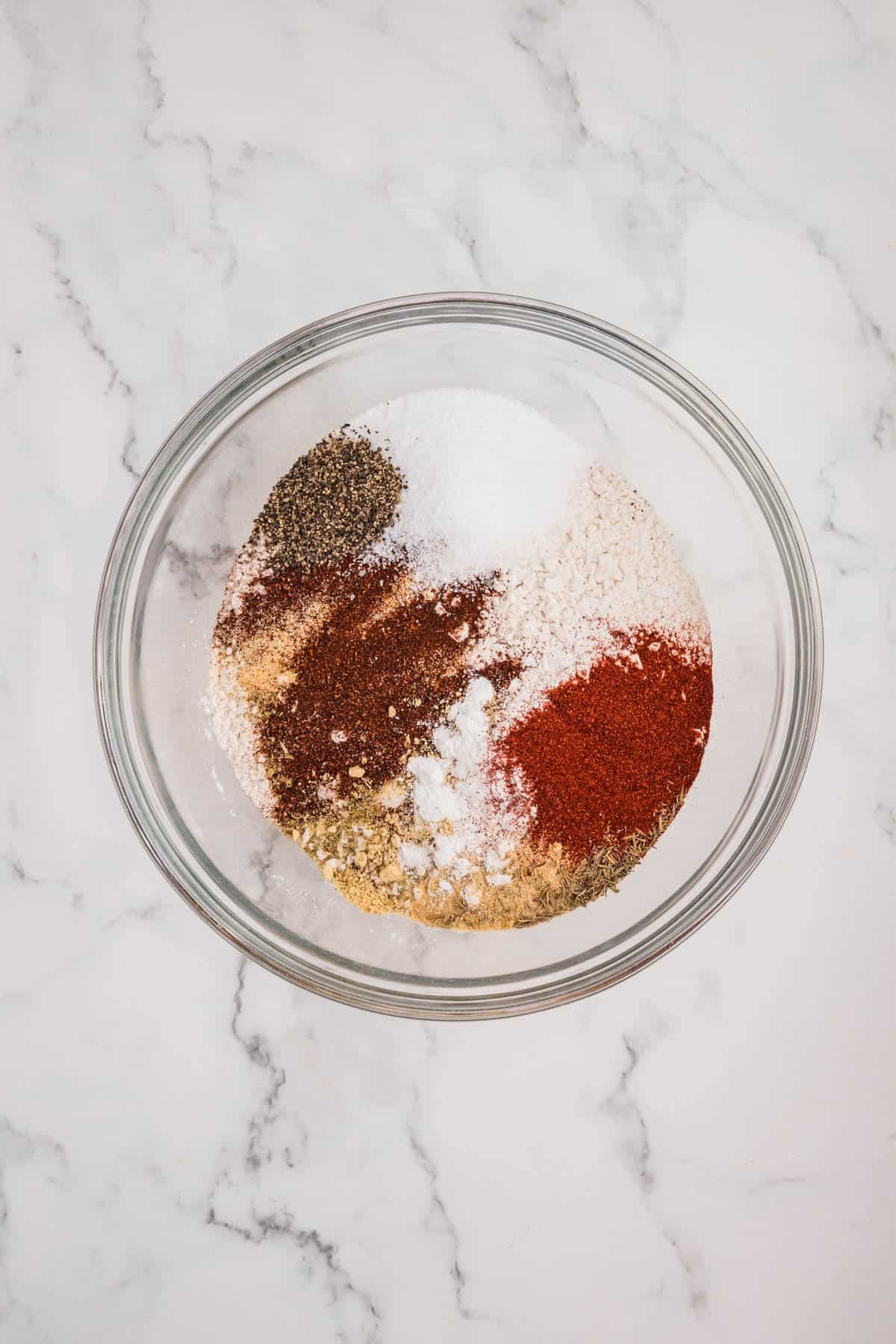 Flour and spices being combined in a large bowl to make a dredging mixture.