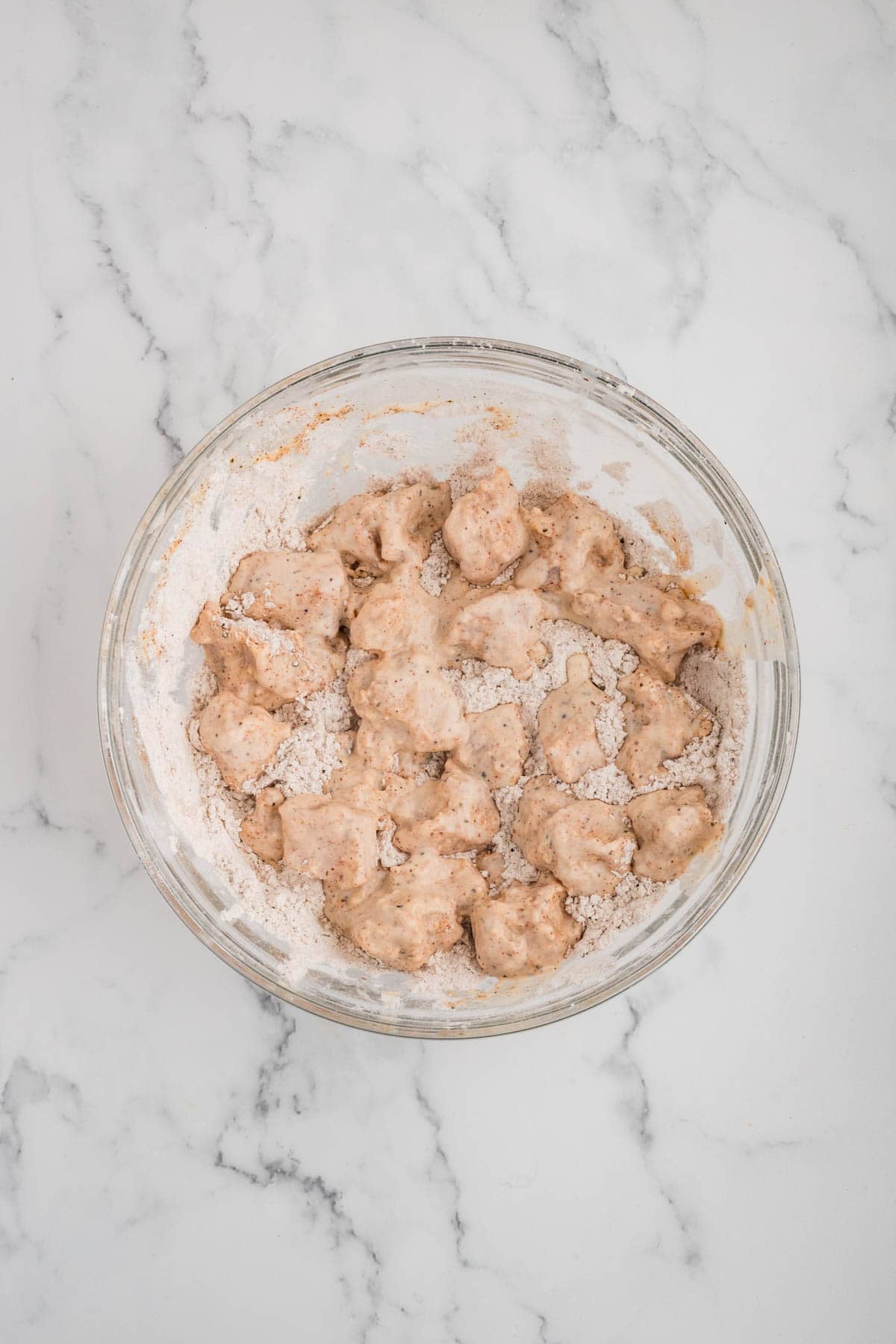 Dredging chicken pieces in flour for a second time.