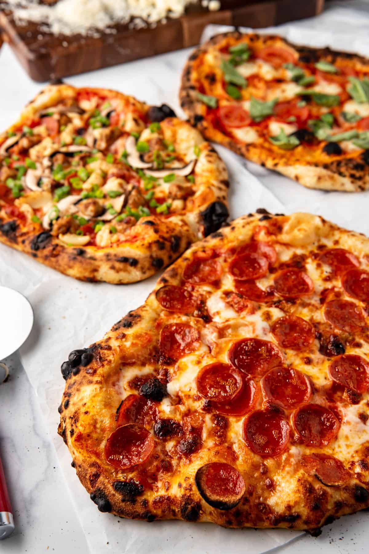 An overhead image of pepperoni sourdough pizza in front of two other sourdough pizza flavors.